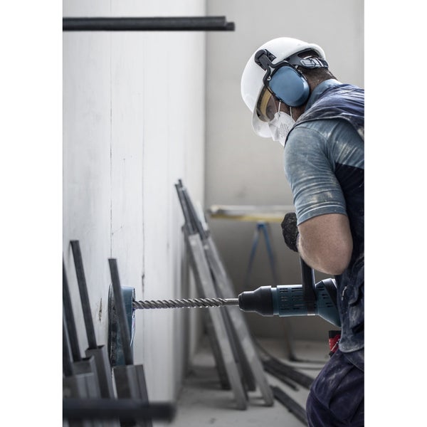 Handwerker bohrt mit einer Bohrmaschine ein Loch in eine Wand.