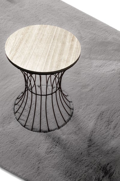 Beistelltisch mit runder Holzplatte und schwarzem Metalldrahtgestell auf einem grauen Hochflor-Teppich.