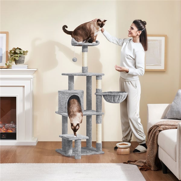Grauer Katzenkratzbaum mit mehreren Ebenen und zwei Siamkatzen in einem hellen Wohnzimmer.