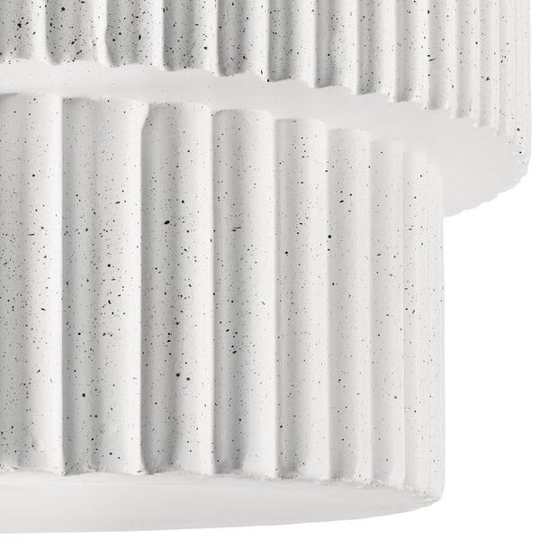 Nahaufnahme einer gerippten Oberfläche aus weißem Material mit schwarzen Sprenkeln.