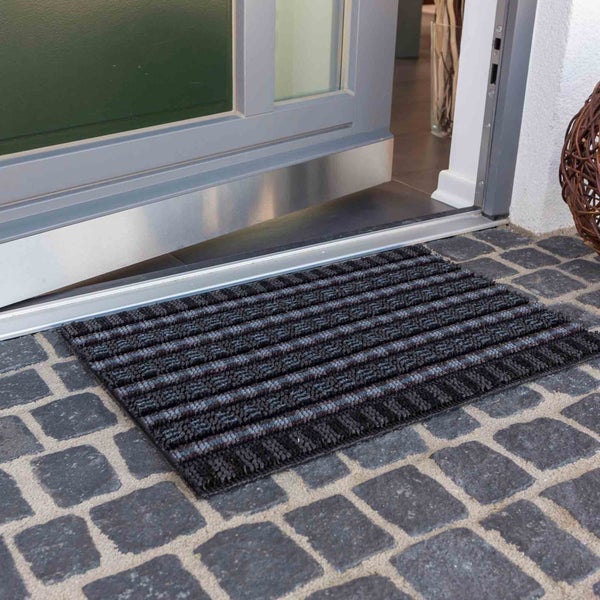 Schmutzfangmatte vor einer Haustür auf Steinboden