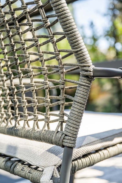 Nahaufnahme der Rückenlehne eines Gartenstuhls mit Seilgeflecht, Metallrahmen und Sitzpolster.