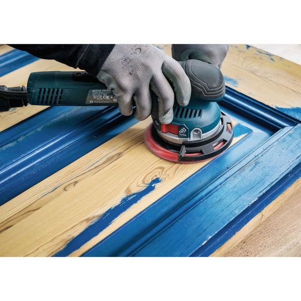 Eine Person schleift mit einem Exzenterschleifer ein Holzbauteil