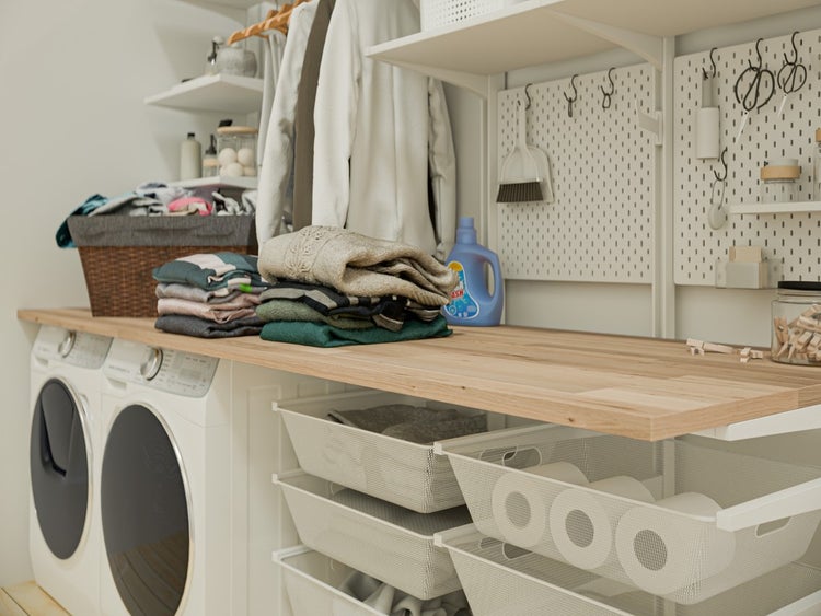 Organisierter Hauswirtschaftsraum mit Waschmaschinen, Holz-Arbeitsplatte, Lochwänden, Regalen und ausziehbaren Gitterkörben zur Aufbewahrung.