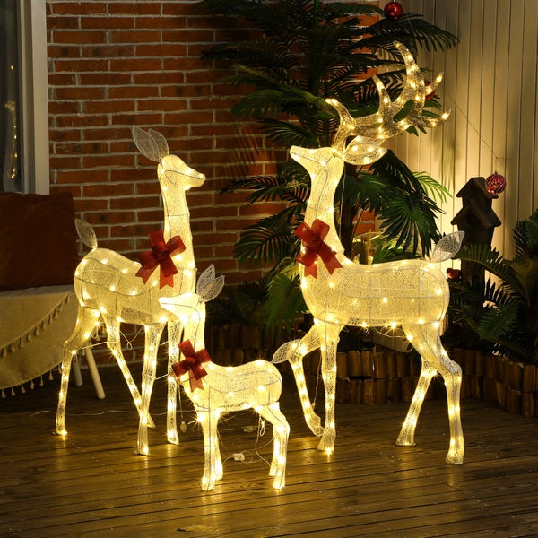LED Weihnachtsdekoration Rentierfamilie bestehend aus drei Figuren mit warmweißer Beleuchtung und roten Schleifen auf einer Holzterrasse.