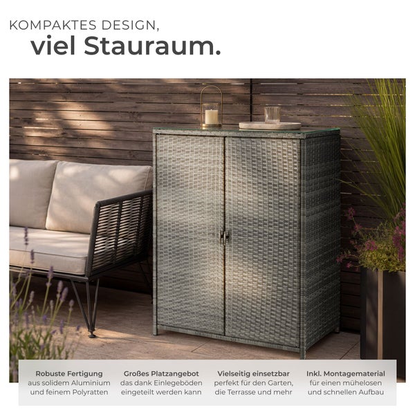 Outdoor-Gartenschrank aus Polyrattan und Aluminium mit zwei Türen und Glasplatte, auf einer Terrasse neben Loungesofa und Holzzaun.