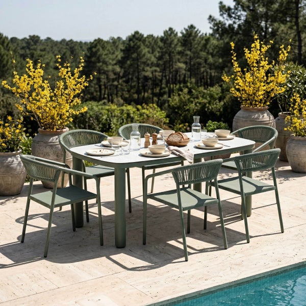 Modernes Garten-Essset bestehend aus einem hellen Tisch und sechs grünen Seilgeflechtstühlen auf einer sonnigen Terrasse am Pool.