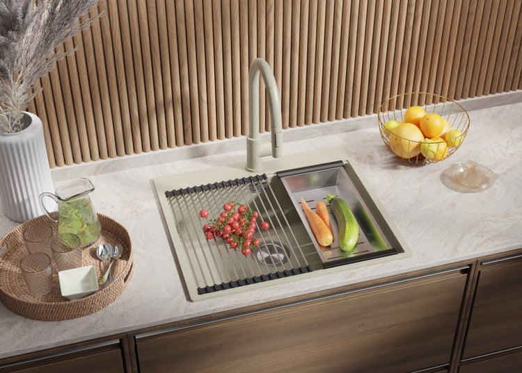 Küchenspüle mit Armatur, Abtropfgestell, Einsatzbecken und diversen Lebensmitteln auf einer Küchentheke.