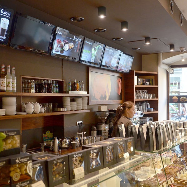 Innenansicht eines Cafés mit Theke, Regalen, Bildschirmen und Beleuchtung