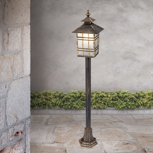 Außenstehleuchte im antiken Design, Laternenform aus Metall und Glas, platziert auf einer befestigten Terrasse im Garten.