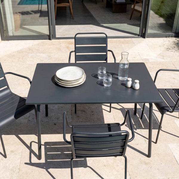 Modernes Garten-Essgruppenset aus Metall mit rechteckigem Tisch und vier Stühlen auf einer hellen Steinterrasse.