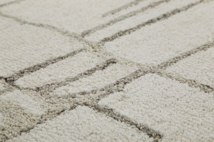 Nahaufnahme eines hellen Teppichs mit Schlingenflor und dunklem geometrischem Linienmuster.