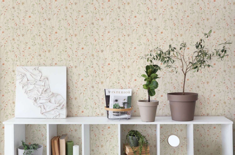 Vliestapete mit zartem Wiesenblumenmuster in einem Wohnraum mit weißem Regal und Pflanzendekoration