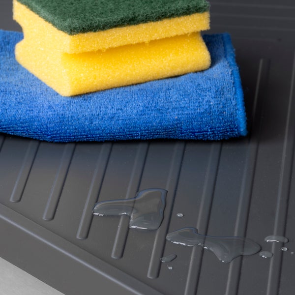 Abtropfmatte mit gerillter Oberfläche, Wasserperlen, Mikrofasertuch und Reinigungsschwämmen.