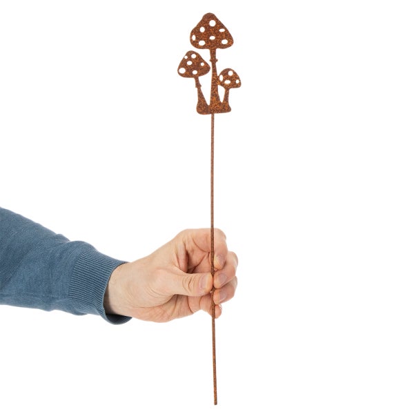 Gartenstecker aus Metall in Rostoptik mit drei Pilzen, von einer Hand gehalten.
