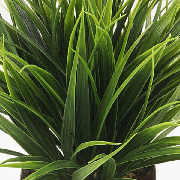 Künstliche Pflanze mit langen grünen Blättern in einem quadratischen schwarzen Übertopf.