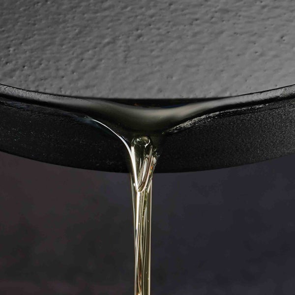 Öl tropft von einer schwarzen gusseisernen Bratpfanne