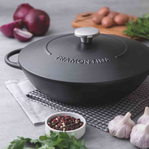 Schwarzer Tramontina Schmortopf aus Gusseisen mit Deckel auf Küchentuch mit Zutaten