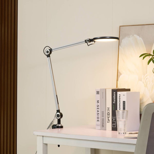 LED-Schreibtischleuchte mit verstellbarem Gelenkarm und Klemmfuß an einem hellen Arbeitsplatz mit Büchern.