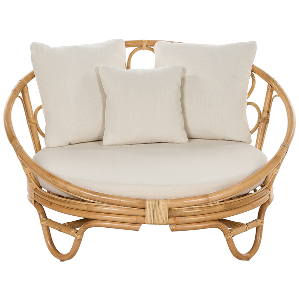 Rundes Sofa aus naturfarbenem Rattan mit hellen Sitzkissen und drei Rückenkissen.