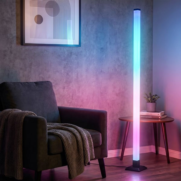 Moderne LED-Stehleuchte mit Farbverlauf in einem Wohnzimmer mit Sessel, Beistelltisch und Wandbild.