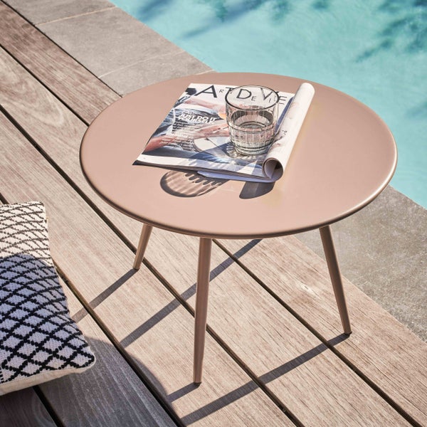 Runder Beistelltisch aus Metall auf einer Holzterrasse am Pool mit einer Zeitschrift und einem Glas Wasser.