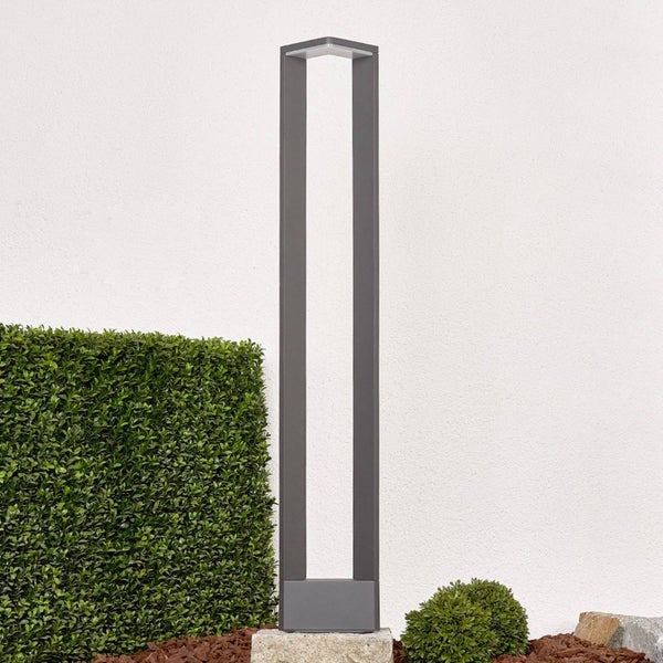 Moderne LED-Außenleuchte in rechteckiger Rahmenform vor einer Hecke im Garten.