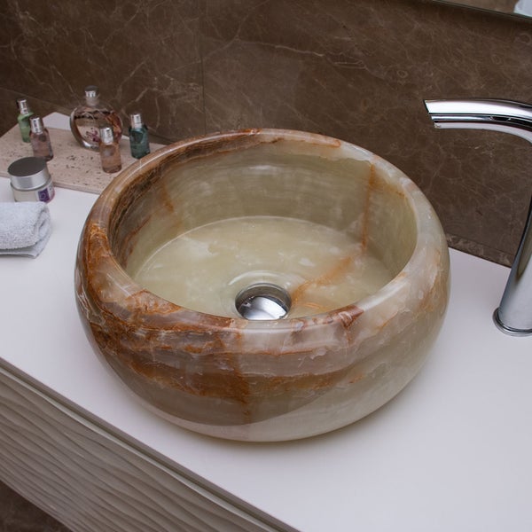 Rundes Aufsatzwaschbecken aus Onyx-Naturstein mit brauner Maserung auf einem weißen Waschtisch neben einer verchromten Armatur.