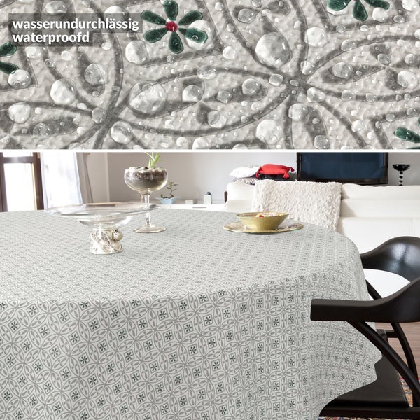 Runde, wasserdichte Tischdecke mit geometrischem Blumenmuster auf einem Tisch, Detailansicht der wasserabweisenden Oberfläche mit Wassertropfen.