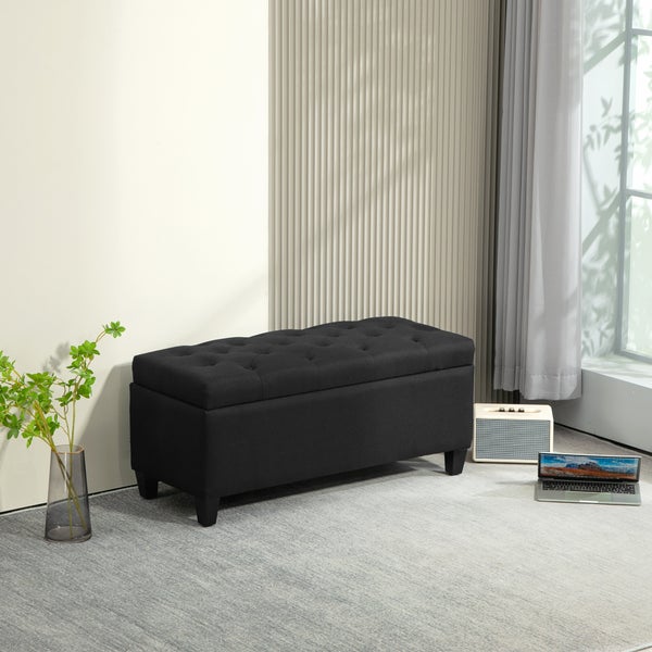 Schwarze Aufbewahrungsbank mit Knüpfheftung in einem hellen Wohnzimmer.