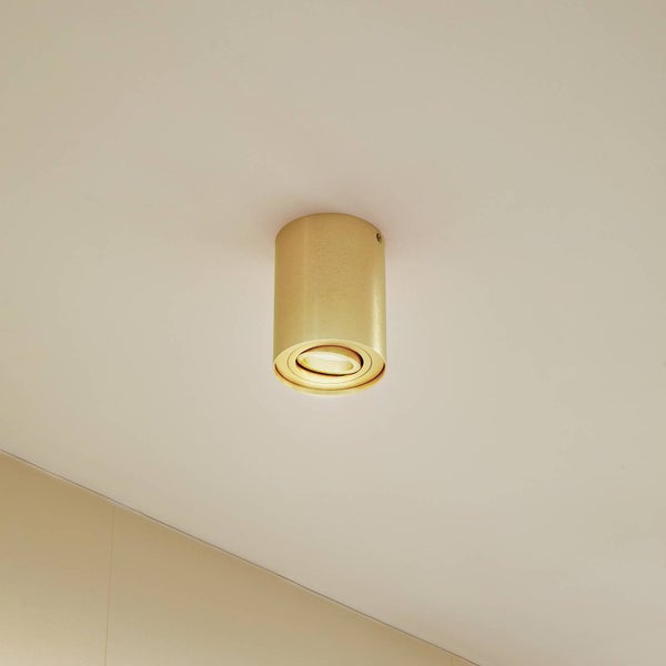 Zylindrischer Deckenaufbaustrahler aus goldfarbenem Metall.
