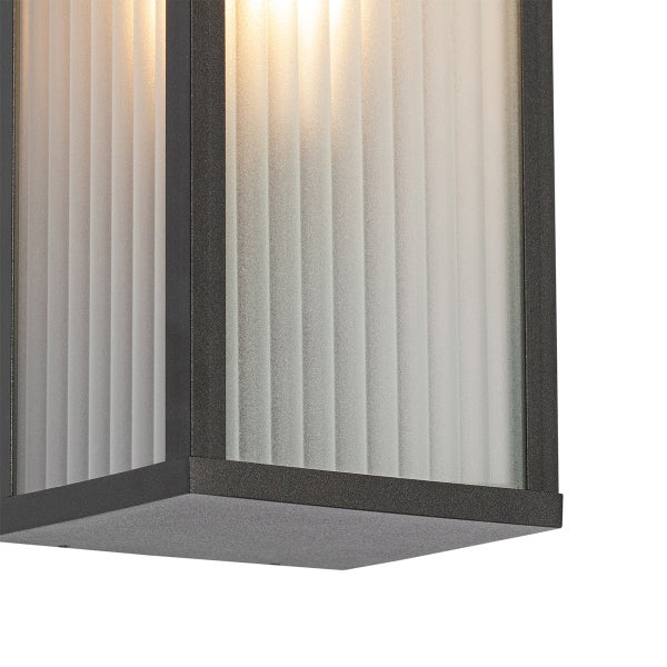 Wandleuchte mit geriffeltem Glas und dunklem Metallrahmen.