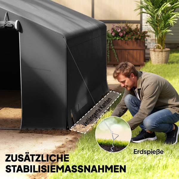 Ein Mann sichert ein graues Lagerzelt im Garten mit verlängerten Kanten und Erdspießen für zusätzliche Stabilität.