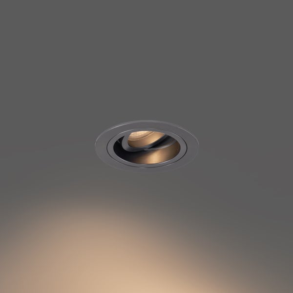 Schwenkbarer Einbaustrahler aus Metall in Anthrazit mit warmem Lichtstrahl.