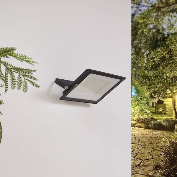 Schwarzer LED-Außenstrahler an einer Wand montiert, Blick auf einen beleuchteten Gartenweg.