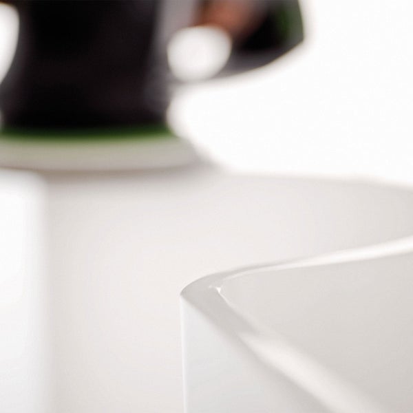 Detailaufnahme eines weißen Waschbeckens mit Schleifmaschine im Hintergrund