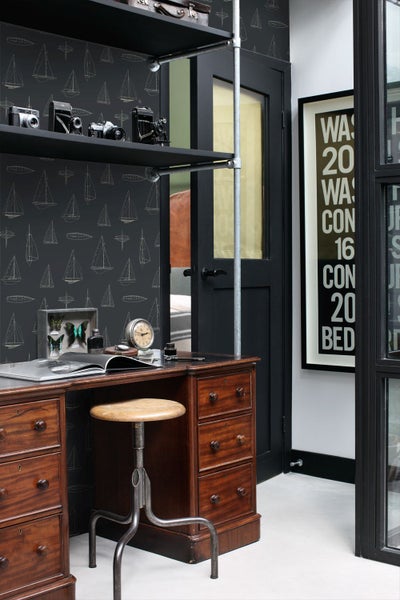 Vliestapete mit Segelboot-Muster in einem organisierten Arbeitszimmer mit antikem Holzschreibtisch und industriellem Hocker.