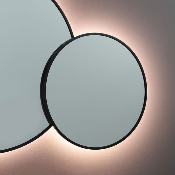 Runder Wandspiegel mit schwarzem Rahmen und warmweißer LED-Hintergrundbeleuchtung, Design aus zwei überlappenden Kreisen.