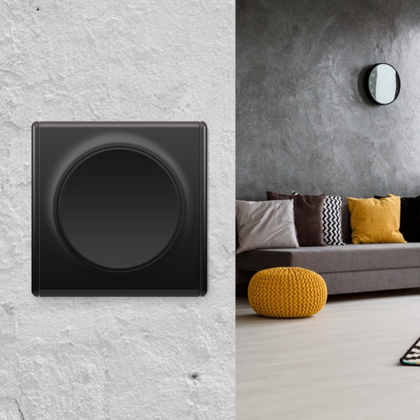 Quadratischer Lichtschalter mit rundem Einsatz in modernem Wohnzimmer mit Sofa und Wanduhr