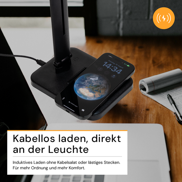 Smartphone beim kabellosen Laden auf einer Ladestation an einer Schreibtischlampe