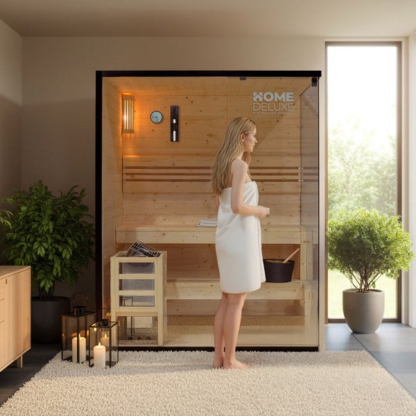 Eine Frau in einem Handtuch vor einer modernen Heimsauna aus Holz der Marke Home Deluxe Logo, platziert in einem hellen, wohnlichen Raum.