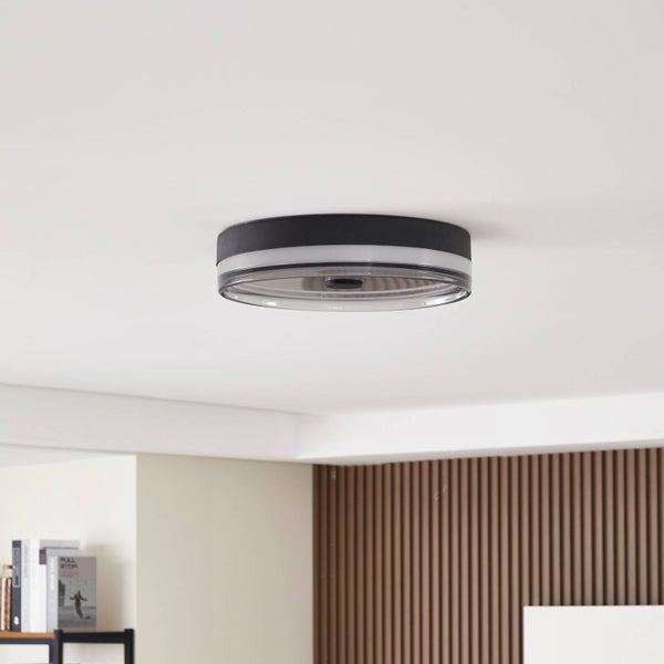 Runde Deckenleuchte im modernen Design mit schwarzem Rand und geriffelter Abdeckung in einem hellen, organisierten Wohnraum.