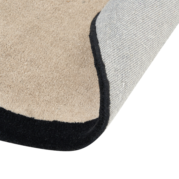 Teppich mit kurzfloriger Oberfläche und umgeschlagener Ecke zeigt die textile Rückseite und die eingefasste Kante