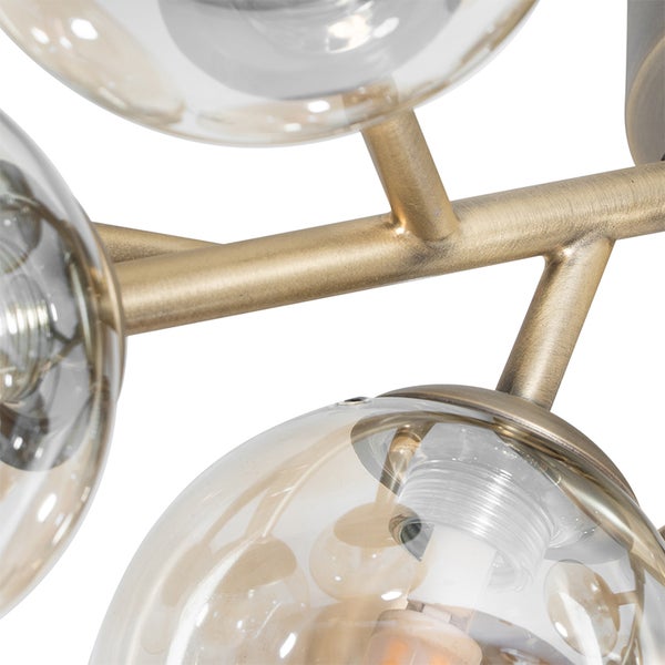 Detailaufnahme einer Deckenleuchte mit goldenem Gestell und kugelförmigen Lampenschirmen