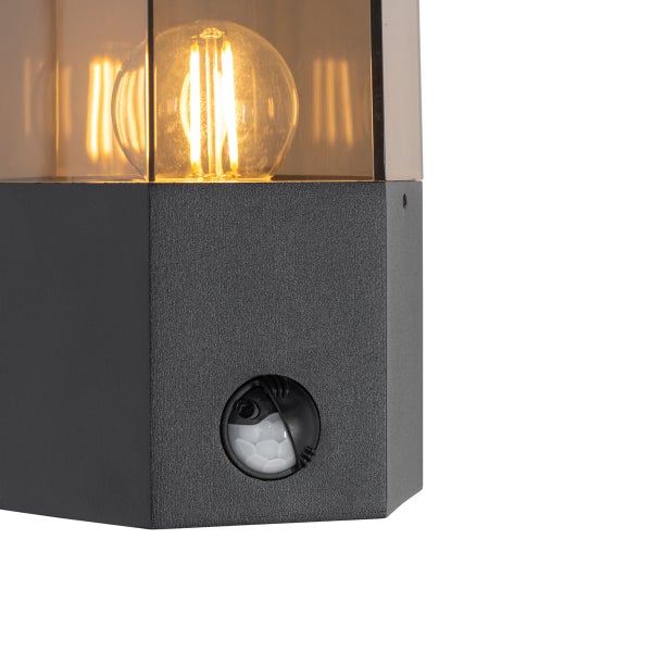 Schwarze Außenwandleuchte mit Bewegungsmelder, Metallgehäuse, transparentem Glas und leuchtendem LED-Filament-Leuchtmittel.