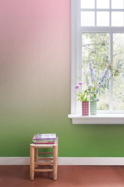 Heller, freundlicher Raum mit farbverlaufender Wand, Blumenvasen am Fenster und einem kleinen Hocker