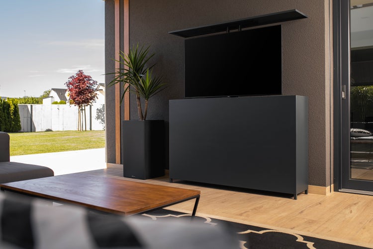 Wohnzimmer im Freien mit Fernsehschrank, Pflanzgefäß und Holztisch