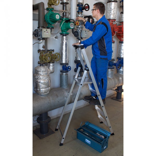 Handwerker auf einer Trittleiter bei der Arbeit an Rohrleitungen.