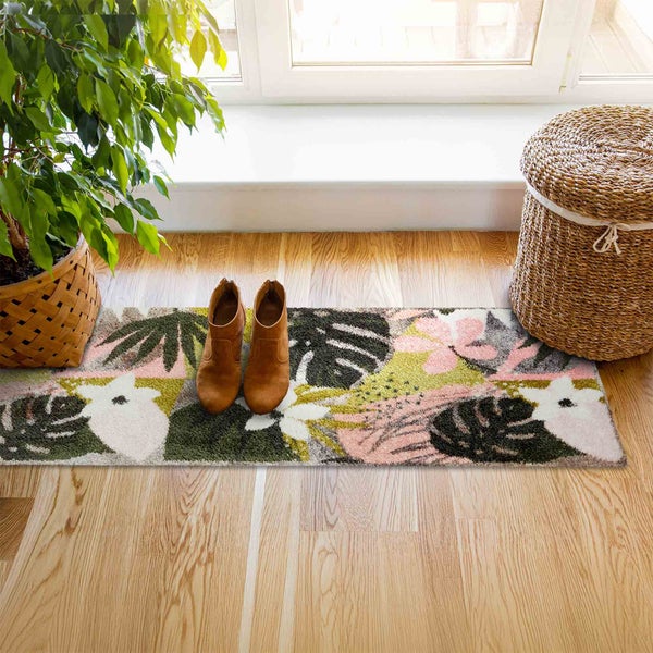 Szene mit Teppich mit Pflanzenmuster, Schuhen, Wäschekorb und Zimmerpflanze in einem hellen Raum