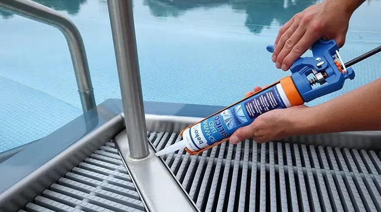 Person verwendet beko Schwimmbad Silikon Kartusche mit Auspresspistole an einem Edelstahl Poolrand